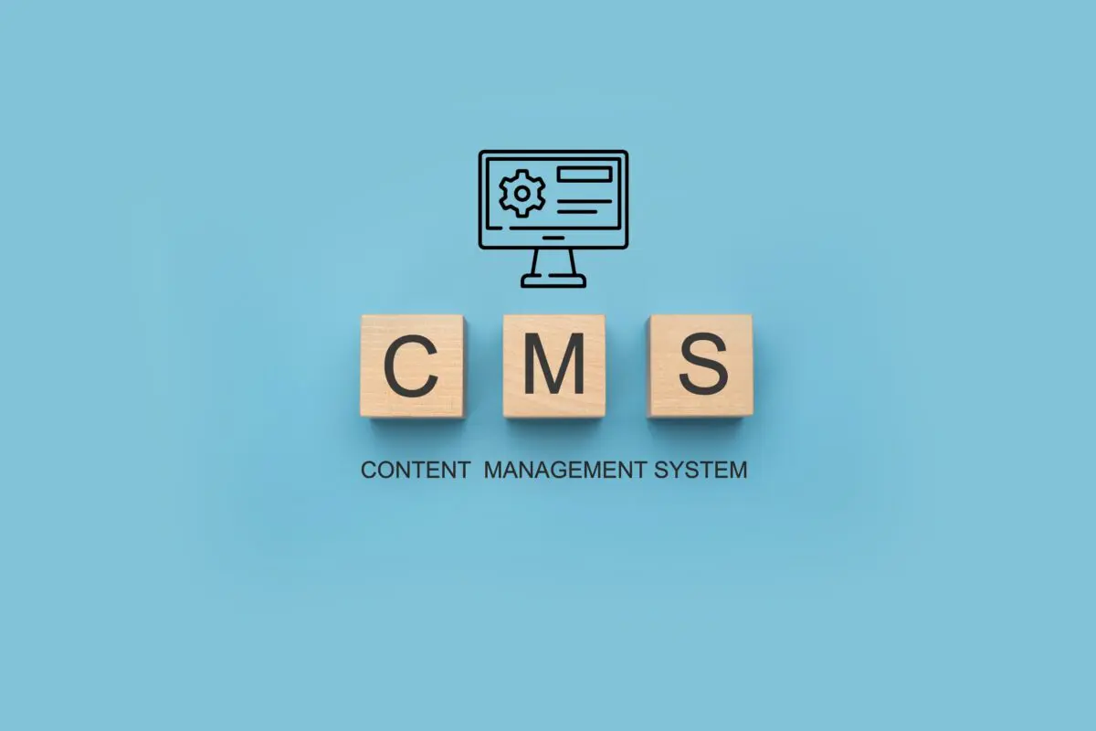Wooden blocks spell CMS above a computer icon, representing Content Management System.