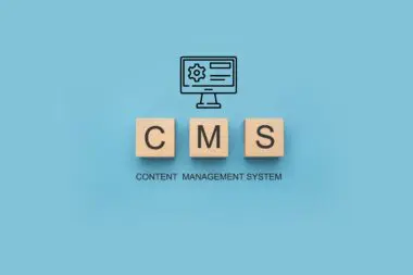 Wooden blocks spell CMS above a computer icon, representing Content Management System.