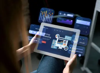 A person holds a tablet displaying a holographic marketing strategy interface with charts and data analytics.
