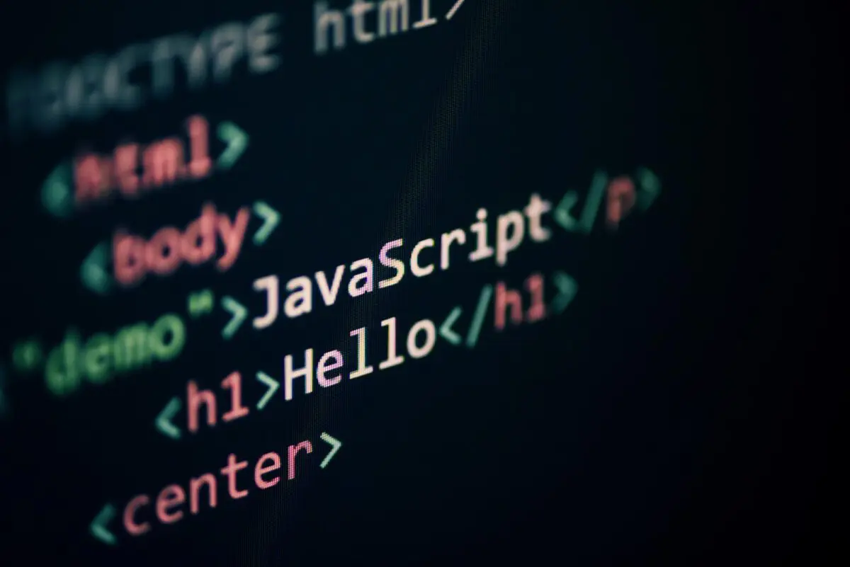 A close-up view of computer code on a dark screen displays HTML tags including body, h1, and paragraph elements.