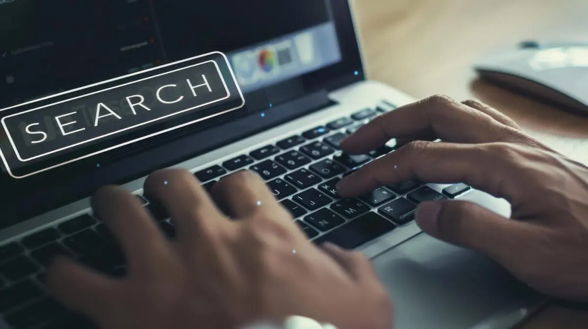 Typing on a laptop with a glowing "SEARCH" overlay, representing front-loaded information.