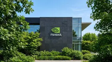 NVIDIA logo on dark stone tiles of facade surrounded by green foliage, symbolizing resilience vs DeepSeek AI chip ambitions.