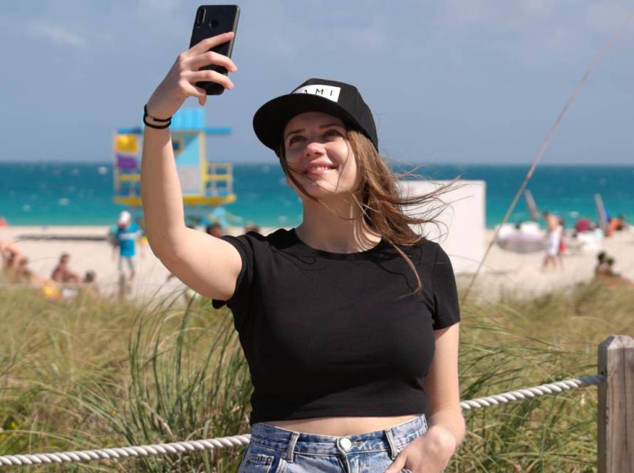 Beautiful woman in Miami Beach takes a selfie on the beach