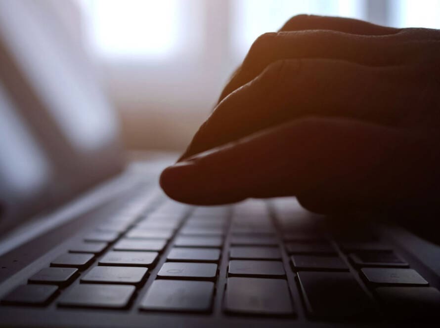 close-up of the hands of a woman writing content into a laptop